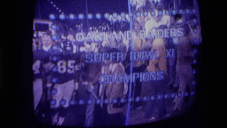 1970s California 8mm frame of a CRT television showing Oakland Raiders Super Bowl XI Champions text over players.