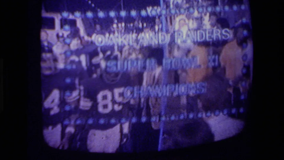 Television screen in 1970s California home-movie footage showing Raiders players beneath Super Bowl XI Champions text.