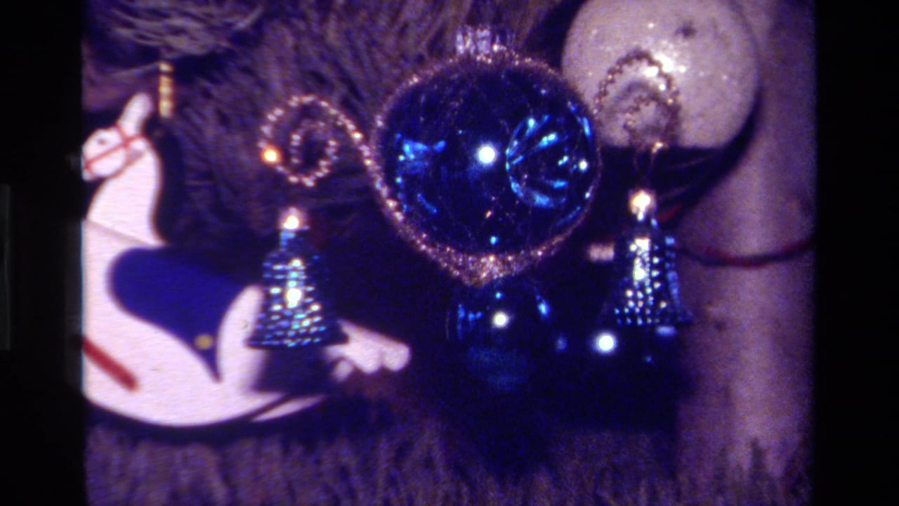 1979 California 8mm close-up of Christmas tree ornaments, including a blue ball, small blue bells, and a white rocking horse.