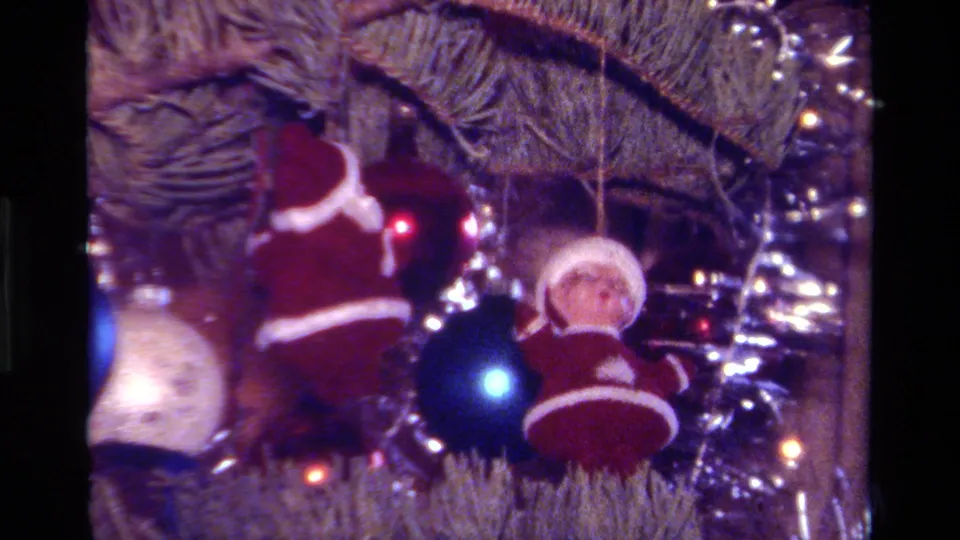 1979 California 8mm close-up of Santa ornaments, a blue ball, tinsel, and tree lights on a Christmas tree.