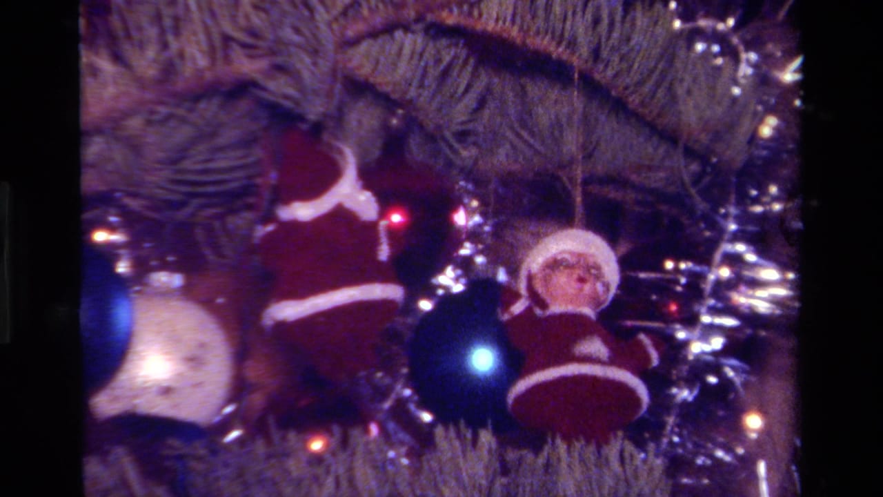 1979 California 8mm home-movie frame showing a decorated Christmas tree with Santa ornaments, metallic baubles, tinsel, and glowing lights.