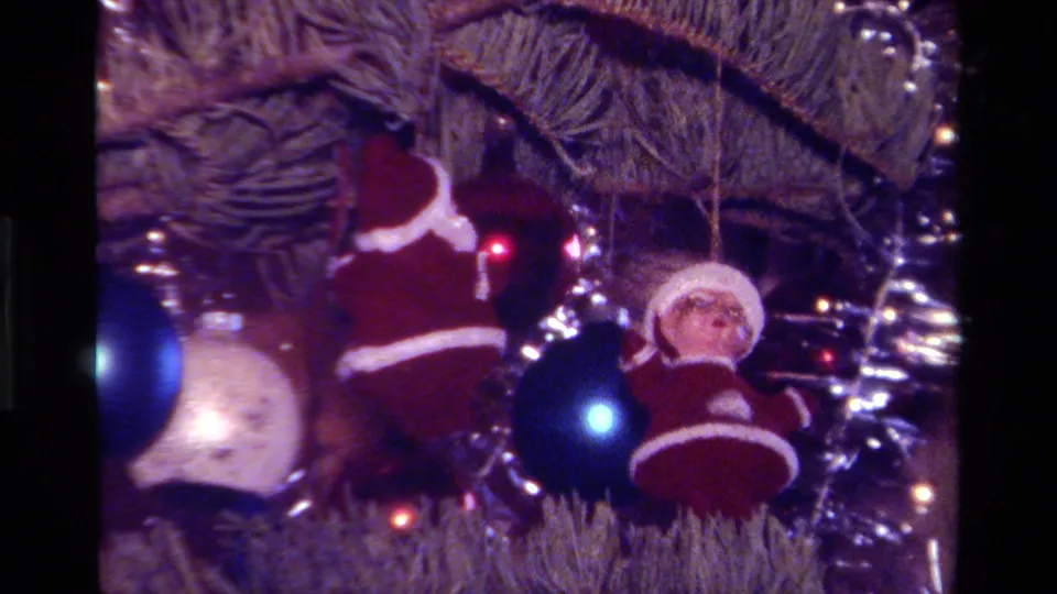 1979 California home-movie still of red-and-white Santa ornaments near blue and silver decorations on a lit Christmas tree.
