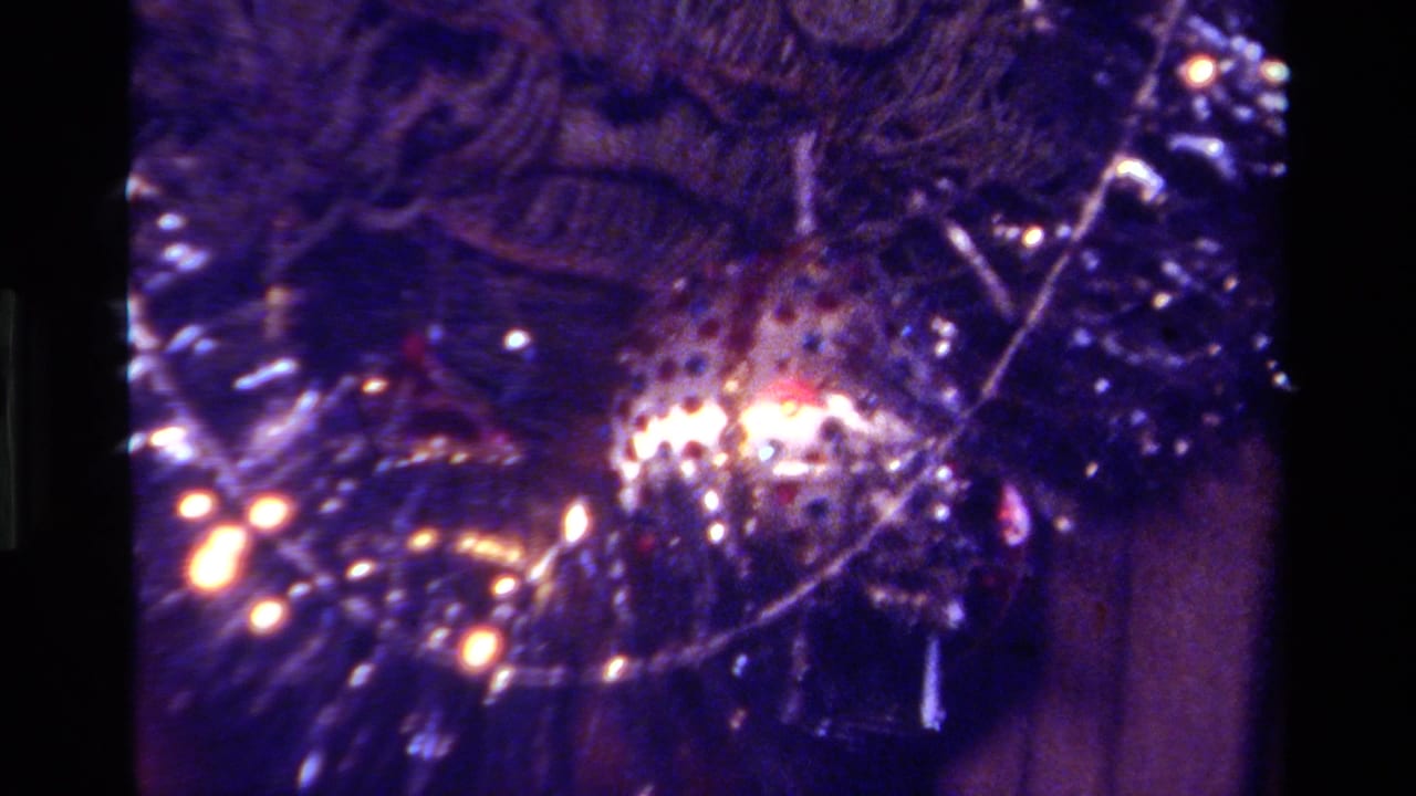 1979 California 8mm close-up of a Christmas tree with tinsel, dark ornaments and glowing reflected lights.
