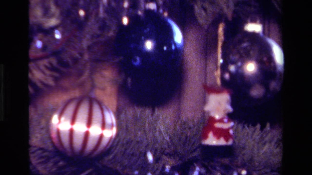 Christmas tree ornaments including a striped ball, dark blue bauble and small Santa figure.