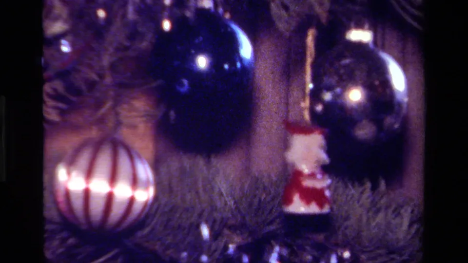 1979 California 8mm frame with striped ornament, dark blue glass bauble and Santa figure among soft-focus tree branches.