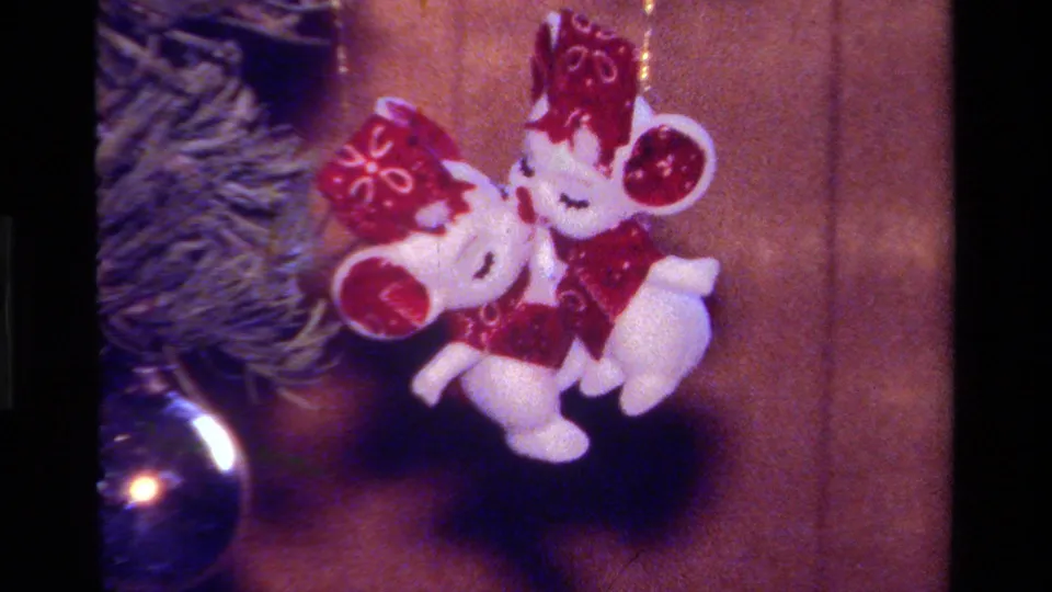 1979 California home-movie close-up of two small mouse ornaments in red clothing hanging beside tree branches and a blue bauble.