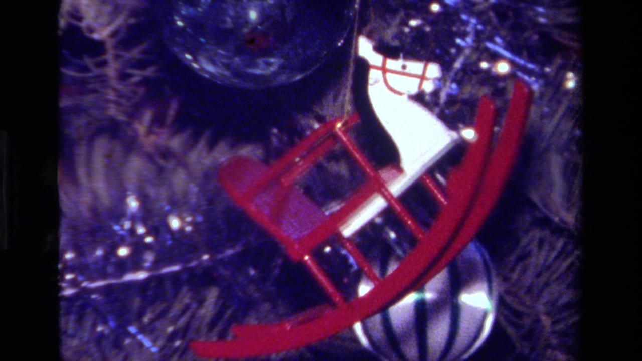 1979 California 8mm close-up of a red rocking horse ornament on a Christmas tree with tinsel and warm lights.