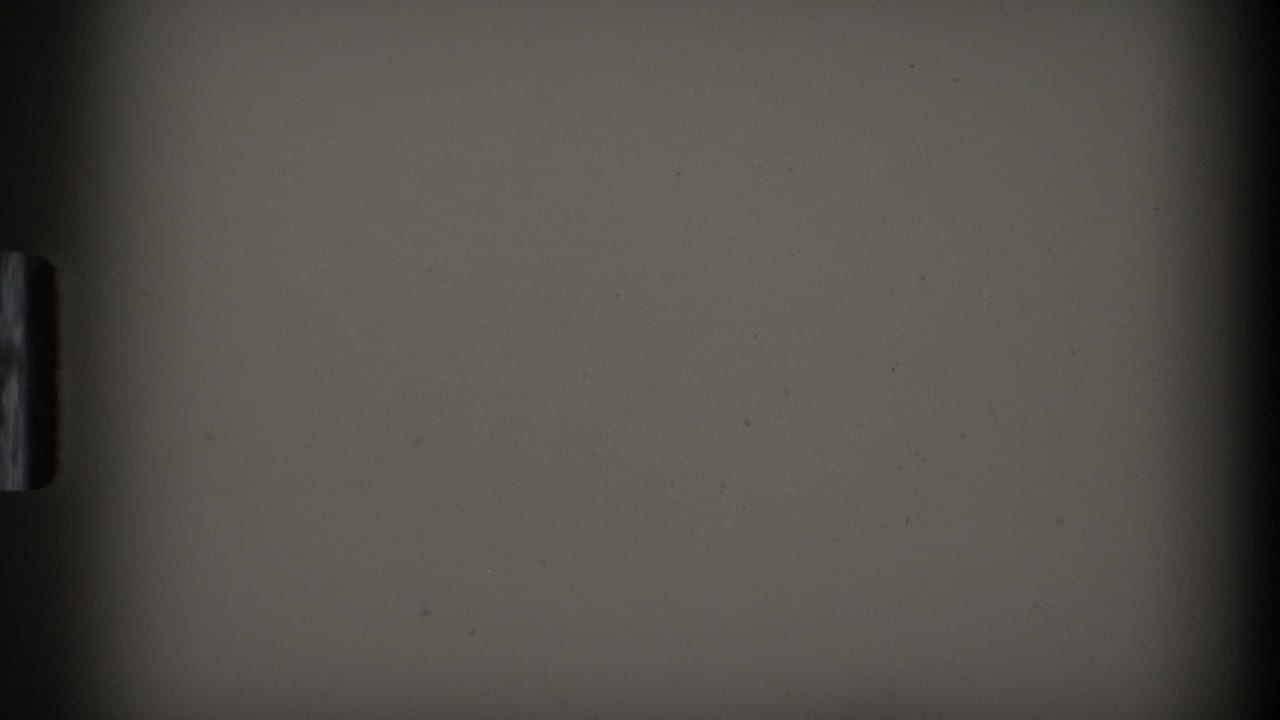 A mostly obscured 8mm frame from the contact sheet, showing a pale surface and dark film edge with no clear subject visible.