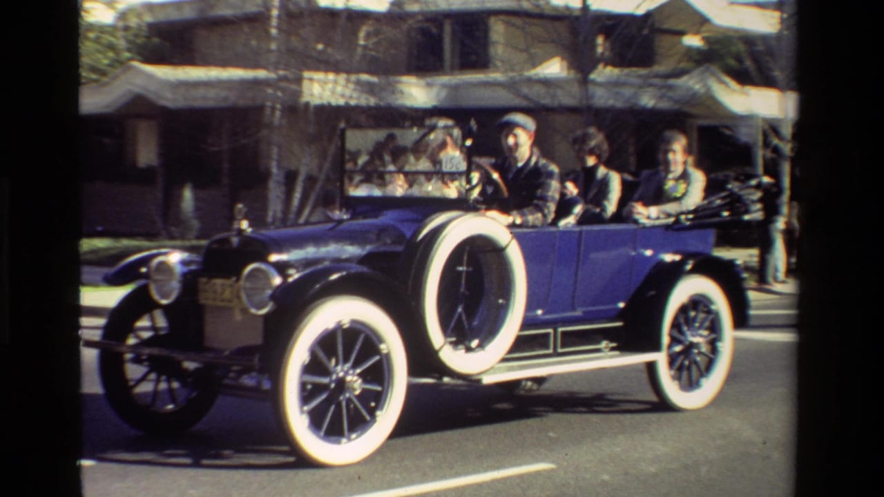 A blue antique open-top car with whitewall tires passes spectators during a California parade, supported by the 1981 clip metadata.