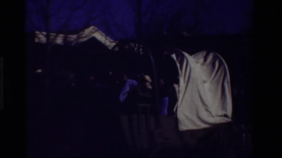 Dark 8mm frame appears to show the covered wagon and parade figures passing in low exposure.