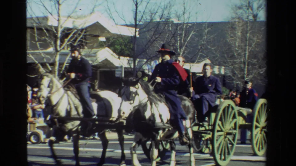 Mounted Union-style reenactors ride past a wagon on a California street in this 1981 home-movie frame.