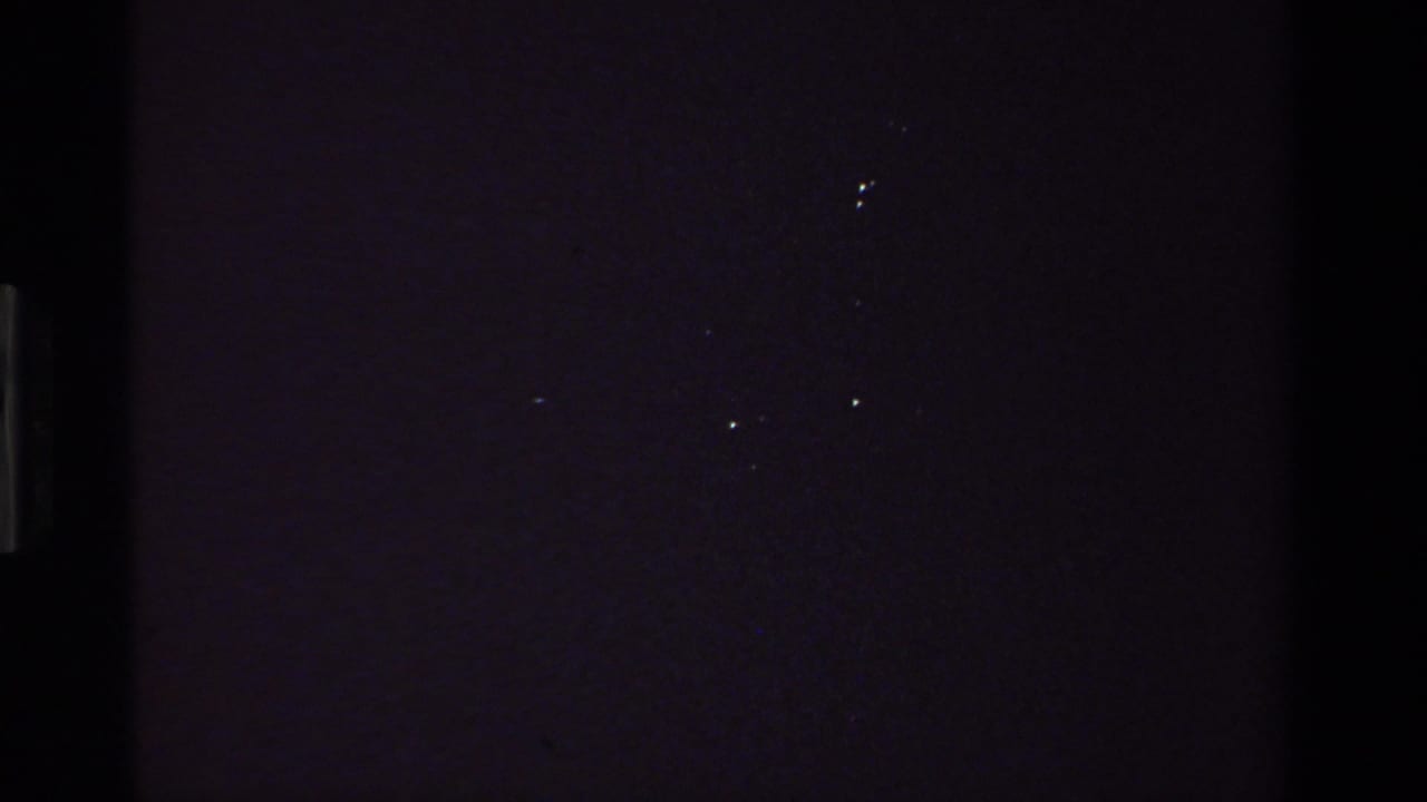 Underexposed opening frame from a 1981 8mm California home movie, with only faint film specks and dark interior tones visible.