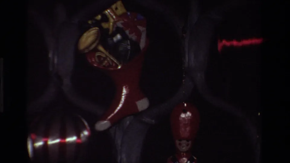 A red Christmas stocking and small ornaments appear near the tree in low-light 8mm home-movie footage.