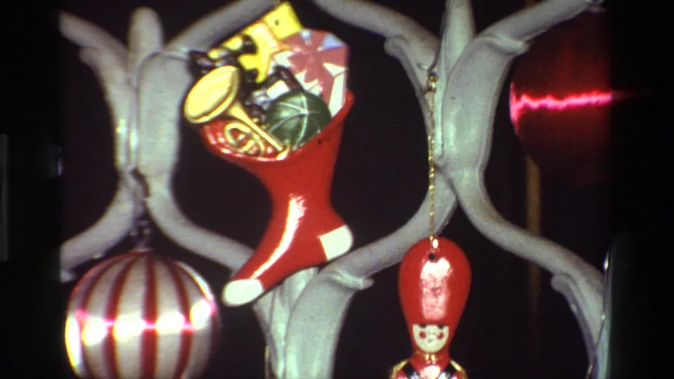 1981 California 8mm frame showing a red toy-filled stocking ornament among pale green branches, striped ball ornament, and red soldier figure.