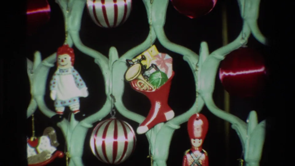 1981 California 8mm frame widening to show a doll ornament, toy-filled red stocking, striped ball, soldier figure, and red bauble.