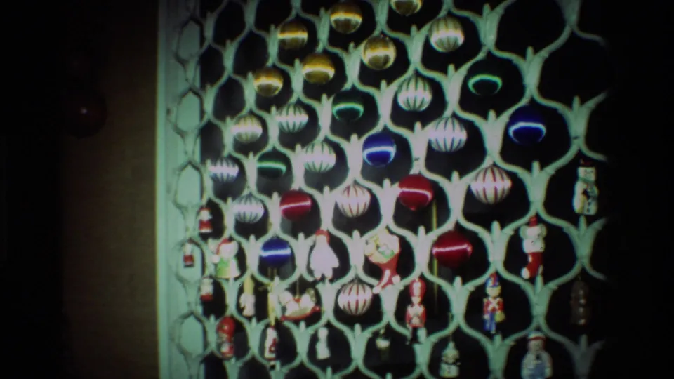 1981 California 8mm frame showing a dense cluster of gold, blue, red, and striped ornaments with small holiday figures below.