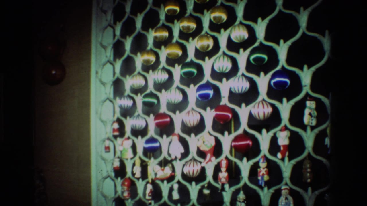 1981 California 8mm frame showing colorful Christmas ornaments hanging from a pale lattice-style display indoors.