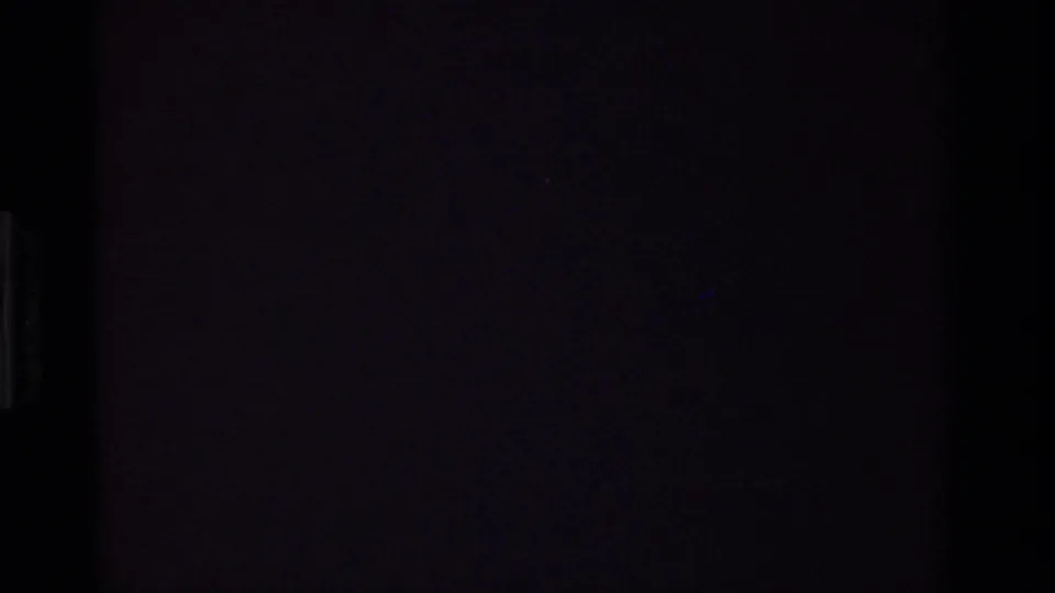 Dark transitional 8mm frame from the Christmas home-movie sequence, with only a faint vertical edge visible.