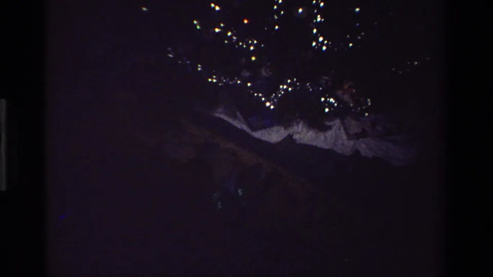 Dim 1981 California 8mm frame with scattered points of Christmas light visible against a dark background.