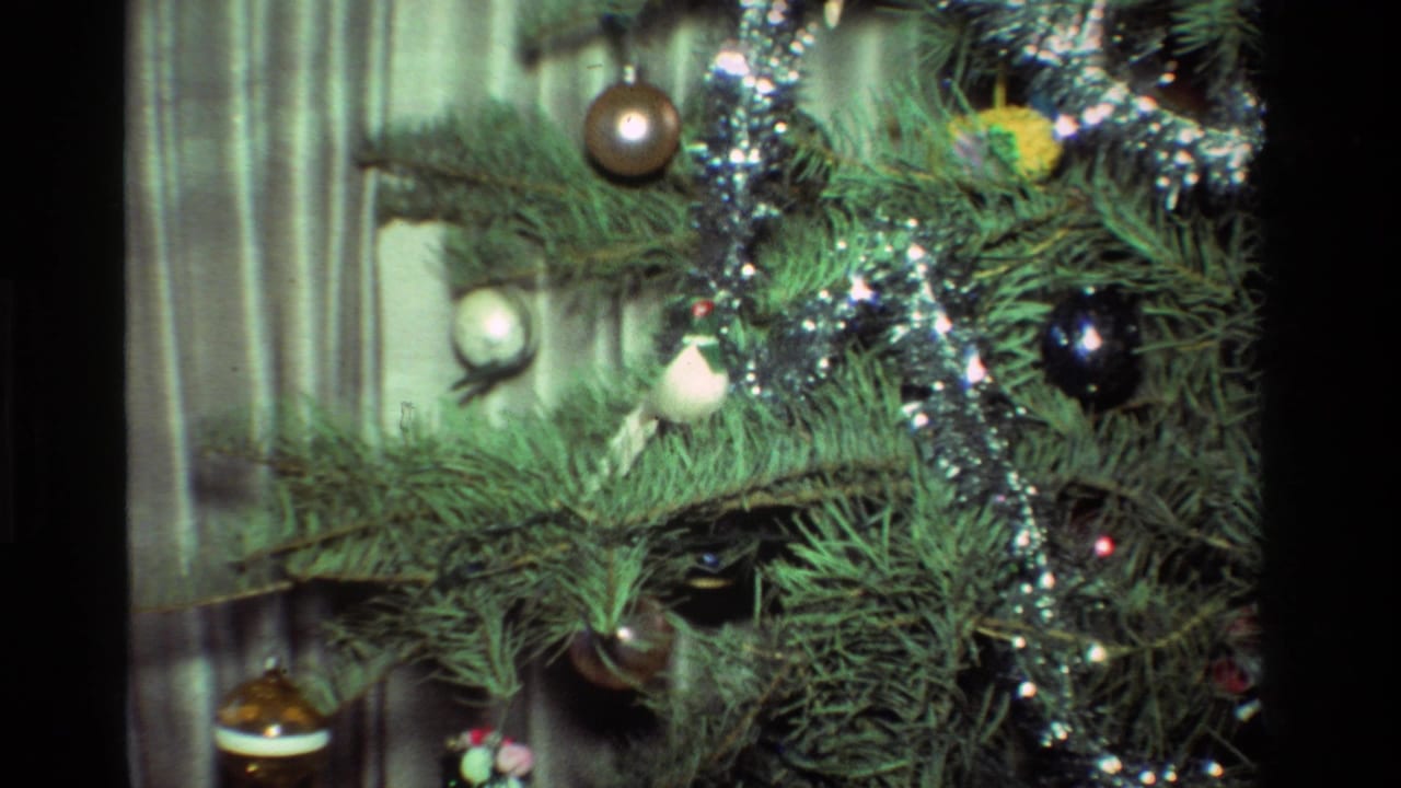 Close view of Christmas tree branches with baubles and silver tinsel.