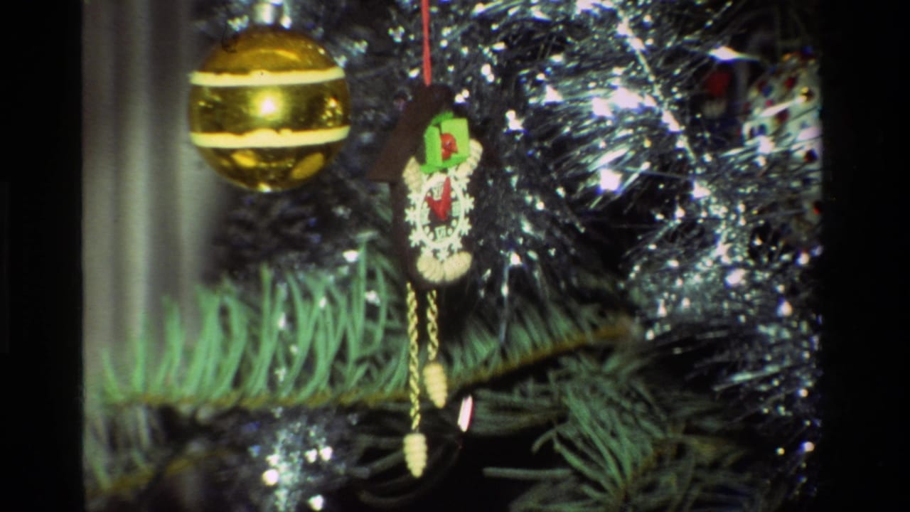 1981 California 8mm close-up of a Christmas tree with a shiny gold ball, cuckoo clock ornament, green needles, and silver tinsel.