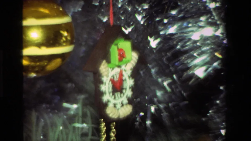 Soft 8mm frame from 1981 California showing a cuckoo clock ornament beside a gold ball on a tinsel-covered Christmas tree.