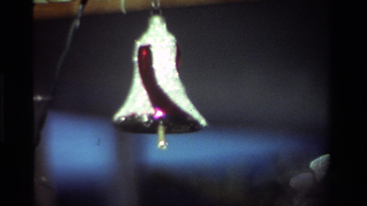 Close view of a red-and-white bell ornament hanging in a dim interior.
