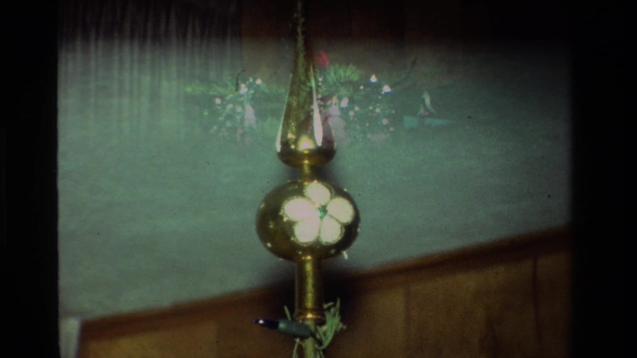 1981 California 8mm frame showing a gold tree topper with a white flower motif on a small Christmas tree.