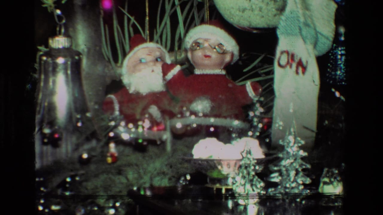 1981 California 8mm frame showing close holiday decorations with Santa figures, shiny ornaments, tinsel, and a white stocking beside a Christmas tree.