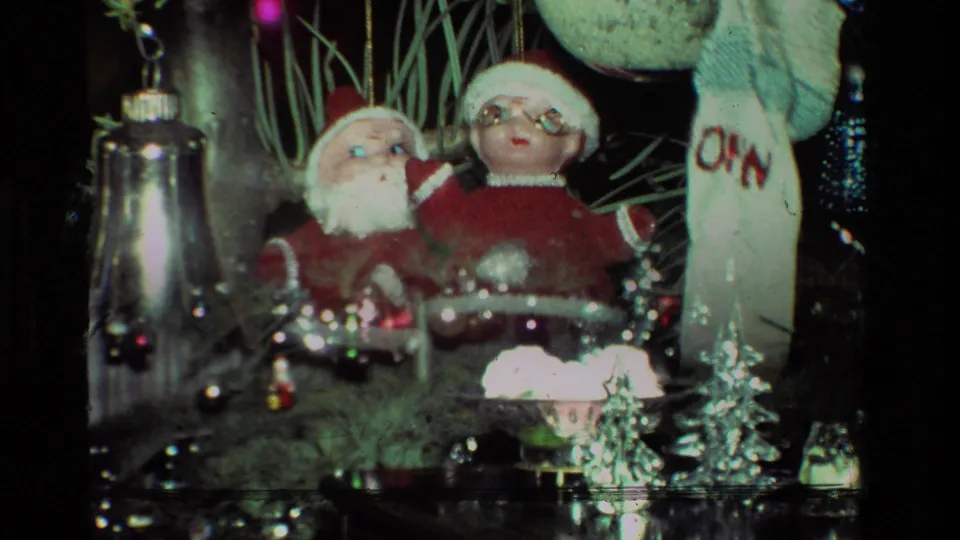 1981 California 8mm frame showing close holiday decorations with Santa figures, shiny ornaments, tinsel, and a white stocking beside a Christmas tree.