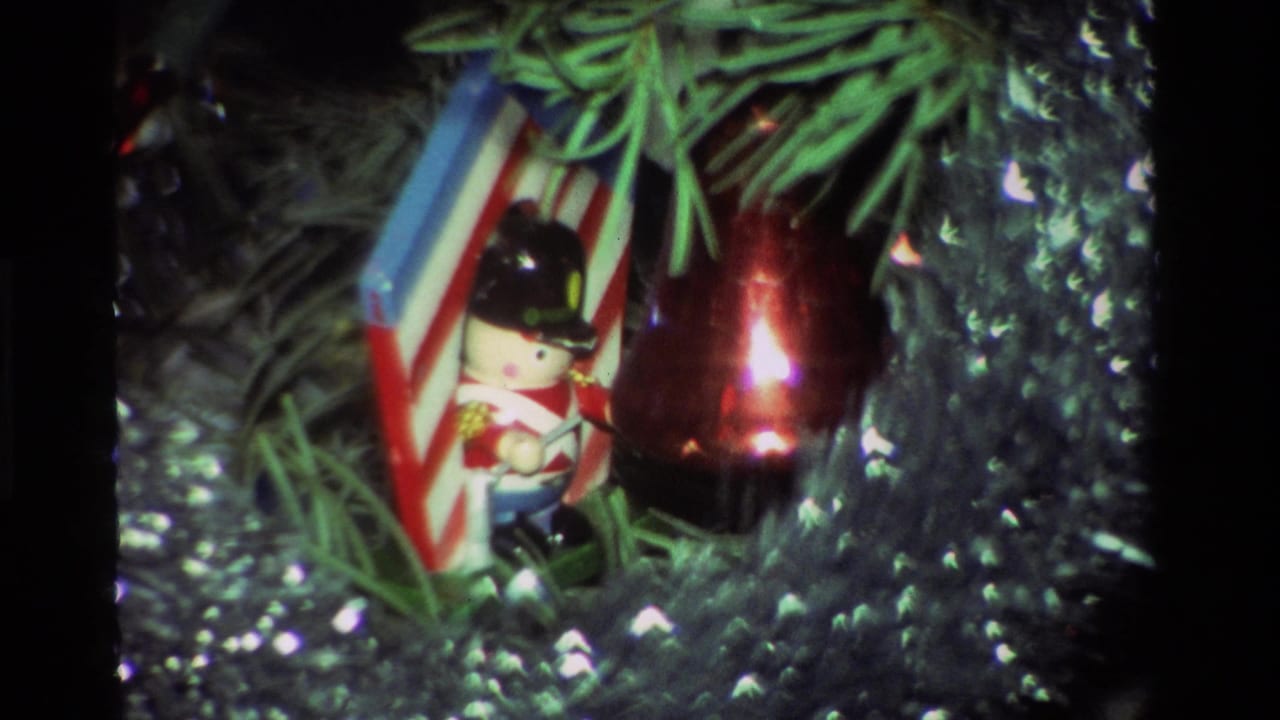 Close-up of a toy soldier ornament with a flag, a red hanging ornament, pine needles, and tinsel in 1981 California home-movie footage.