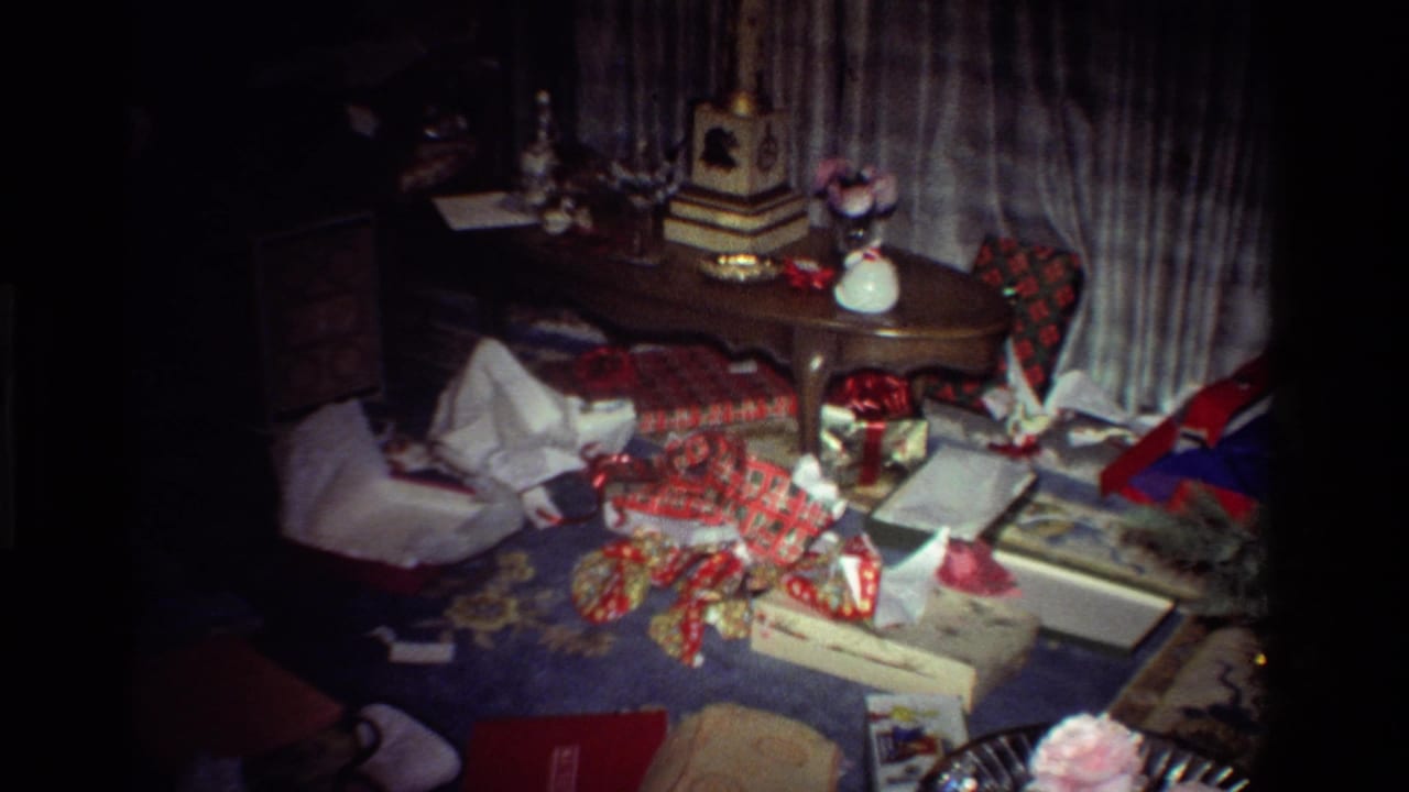 Dim room with wrapping paper, opened boxes, table decorations, and curtains after Christmas gift opening.