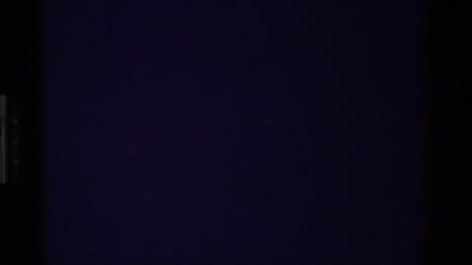 Underexposed 8mm frame from the Christmas home movie with only faint grain, color cast, and edge shadows visible.