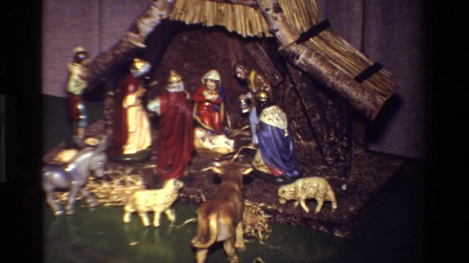 1981 California 8mm frame showing a household nativity scene with Holy Family figures, animals, straw, and a rustic stable.