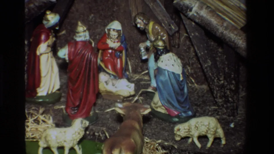 Closer 1981 8mm view of the California nativity display, centering the manger while Mary, Joseph, wise men, sheep, and stable materials remain visible.