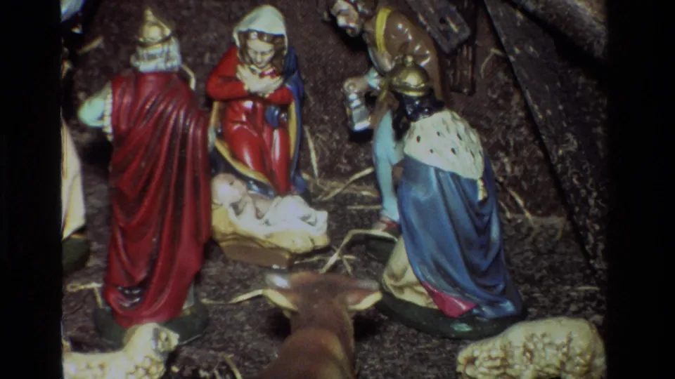 Tight final 1981 8mm view of the California nativity scene, focused on Mary, Joseph, baby Jesus, a wise man, straw, and nearby animal figures.