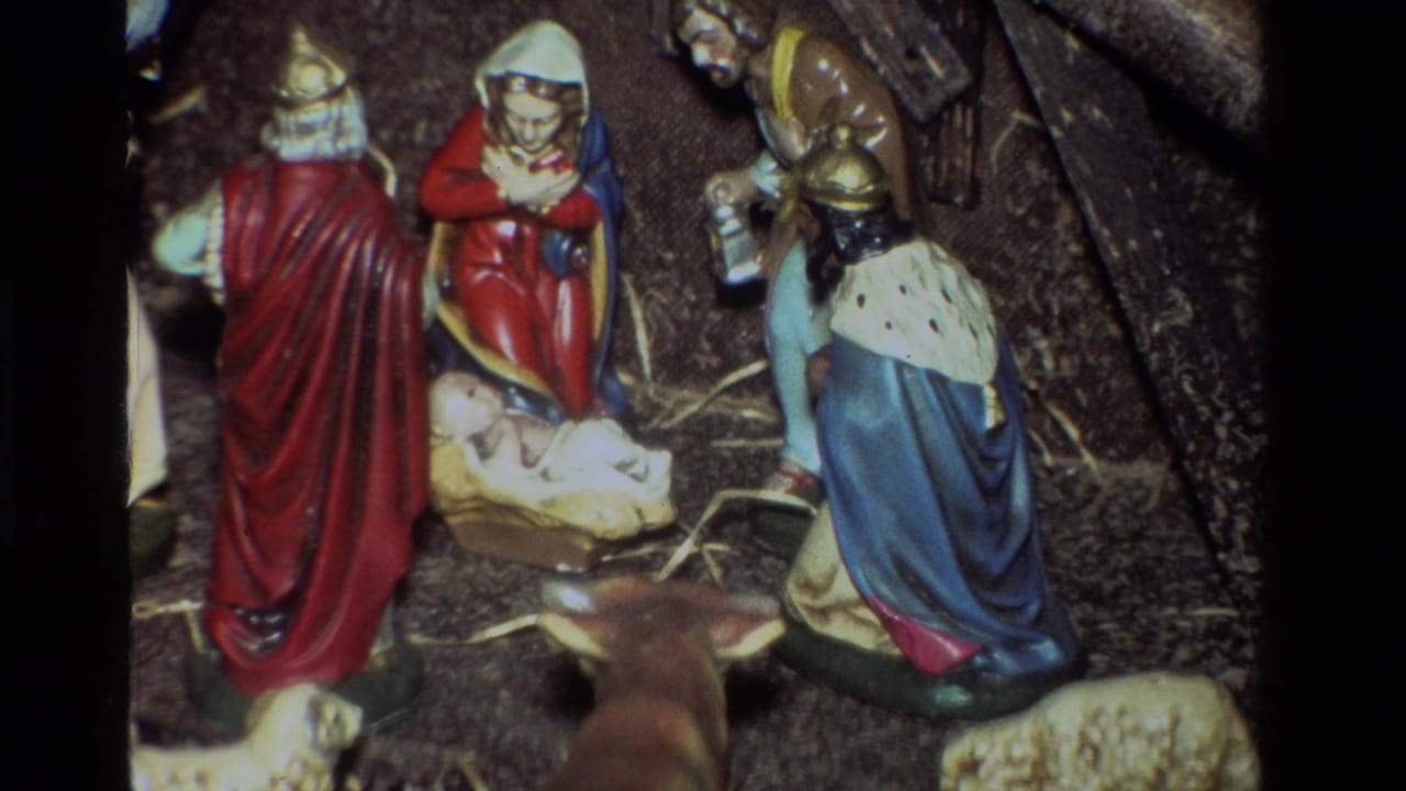 Close view of a Christmas nativity scene with robed figures around baby Jesus in a manger.