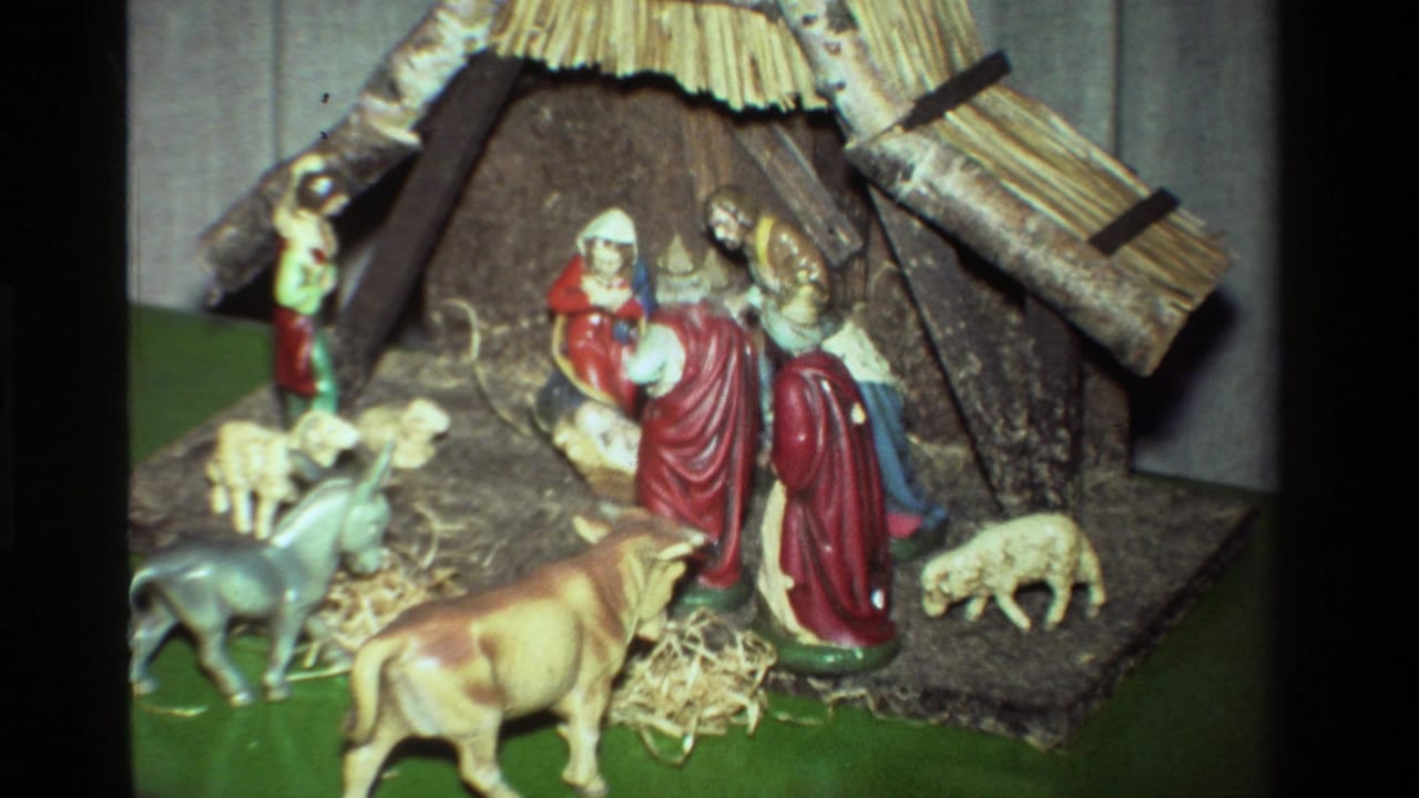1981 California 8mm view of a tabletop nativity set with Mary, Joseph, baby Jesus, animals, straw, and a rustic stable.