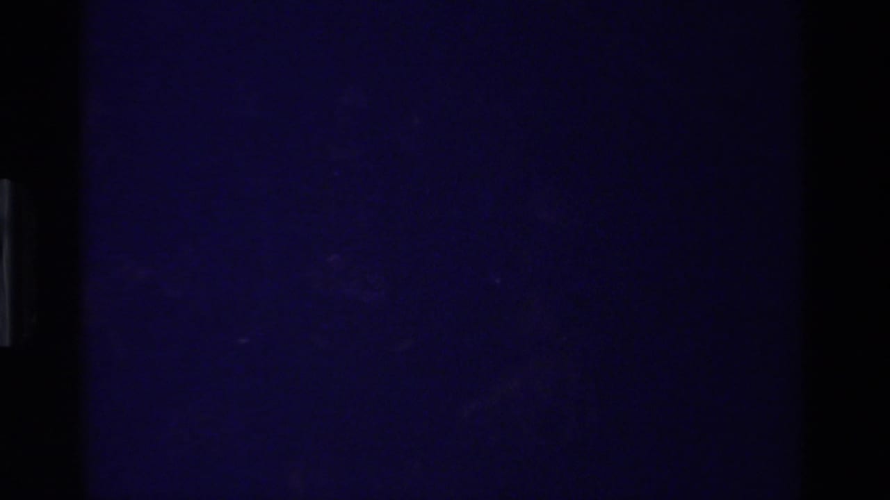 Underexposed 8mm frame from the California home-movie clip, with the subject not yet clearly visible.