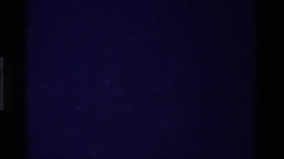 Underexposed 8mm frame from the California home-movie clip, with the subject not yet clearly visible.