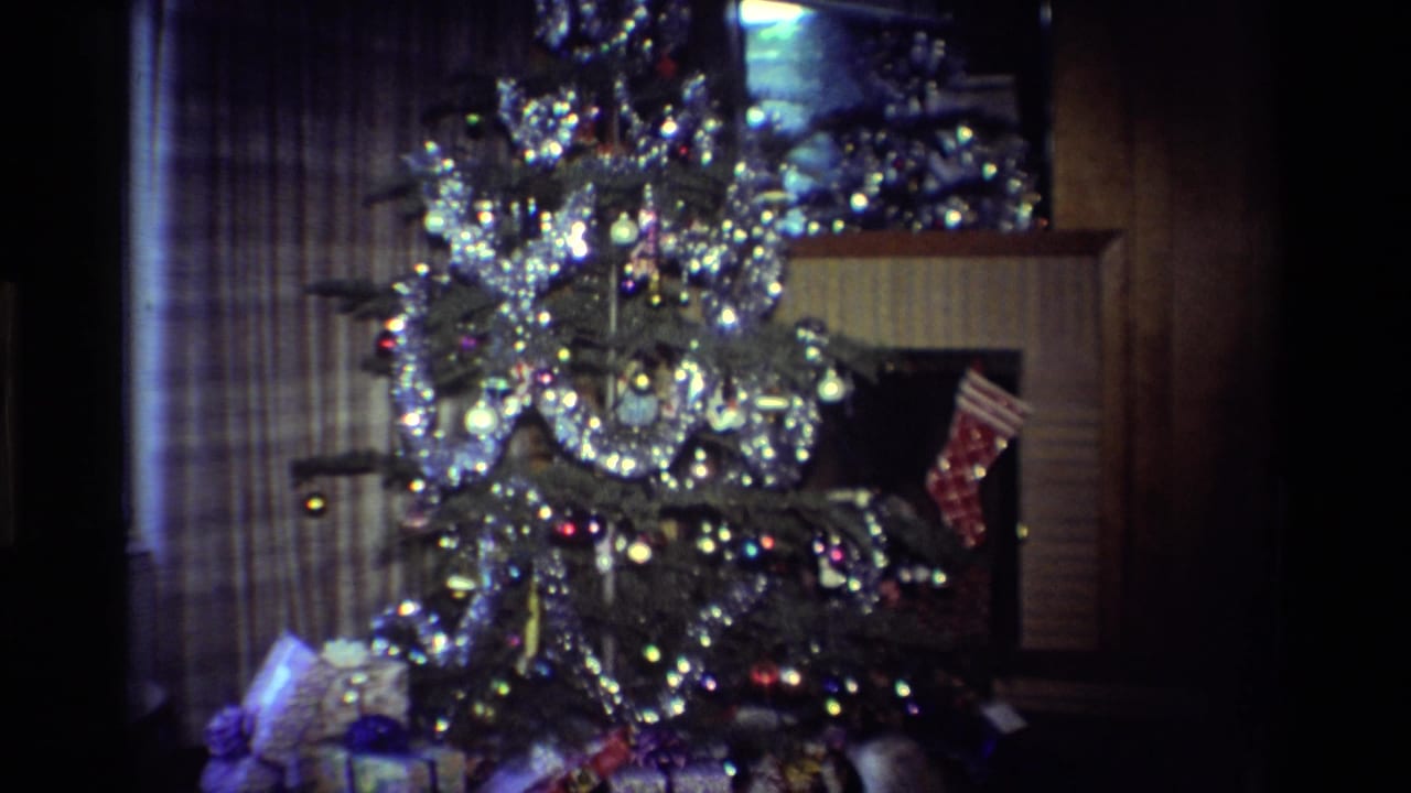 Decorated Christmas tree in front of a fireplace, with presents and stocking visible.