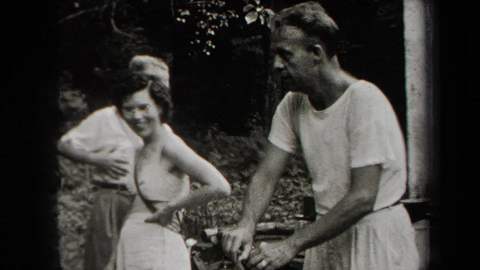 Adults in casual period clothing smile and gather near an outdoor cooking area in metadata-supported 1938 New York footage.