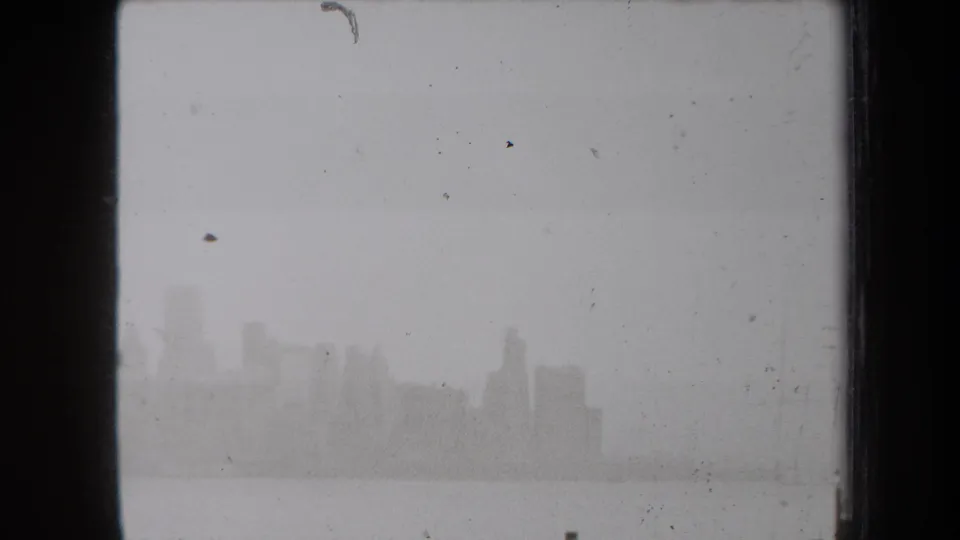 Grainy 1938 New York home-movie view of a distant skyline and water, with scratches and dark frame borders.