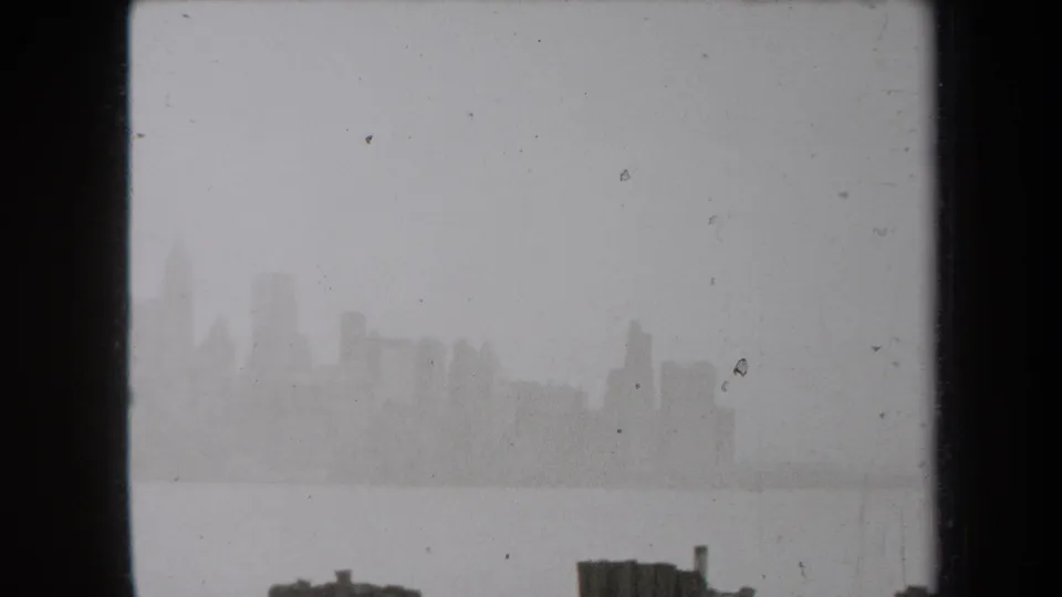 Late-1930s New York skyline view across water, hazy and grainy with dark framing at the edge.
