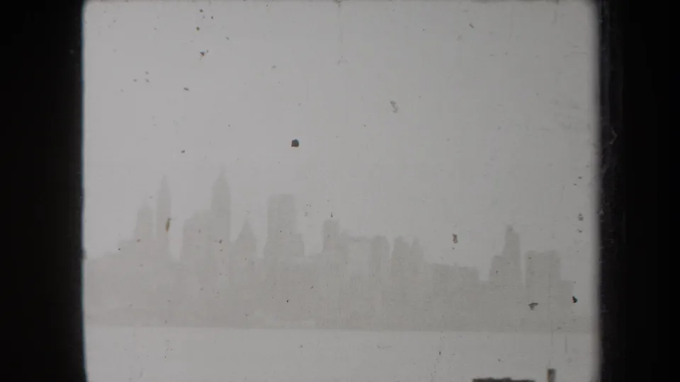 A foggy New York harbor view shows the skyline as a pale silhouette, with visible 8mm frame borders and surface marks.