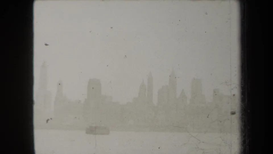 The New York skyline remains faint across the harbor, with fog, low contrast, dust, and scratches visible in the 8mm frame.