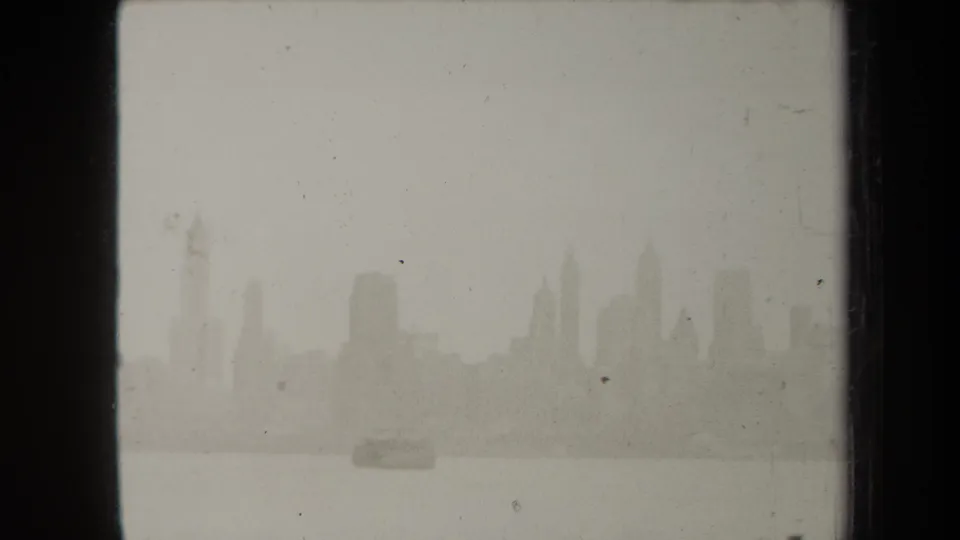 1938 New York skyline appears faintly across the water, framed by dark 8mm film borders and visible dust.