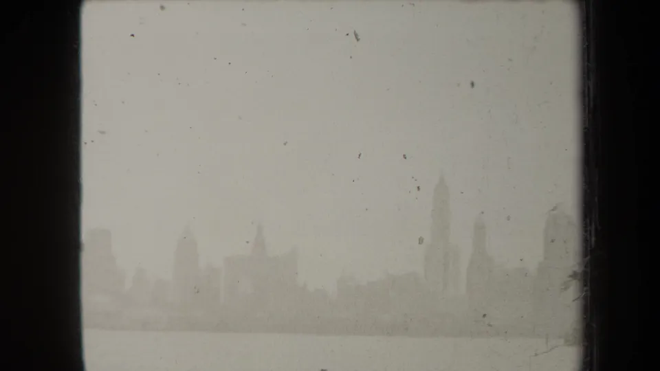 A soft 1938 New York skyline view shows distant high-rises across the river with heavy haze and film wear.