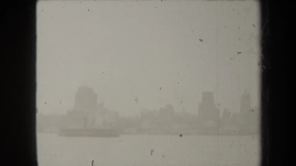 1938 New York home-movie frame showing a hazy waterfront skyline emerging through fog across open water.