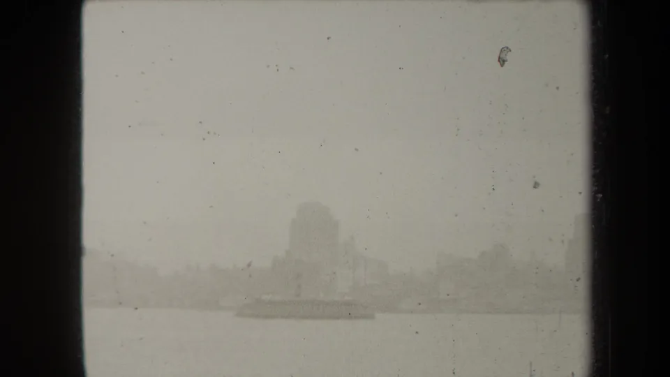 1938 New York waterfront view in thick fog, with faint building masses and a possible low boat on the water.